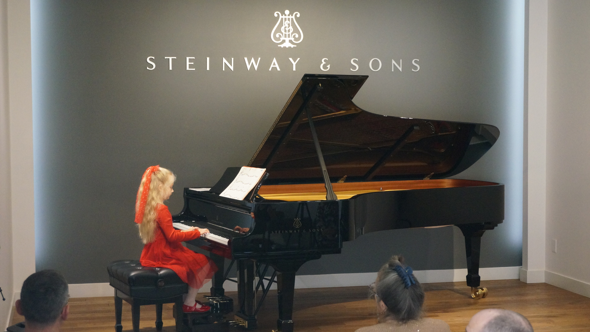 A young student performing at a Steinway grand piano during a recital.